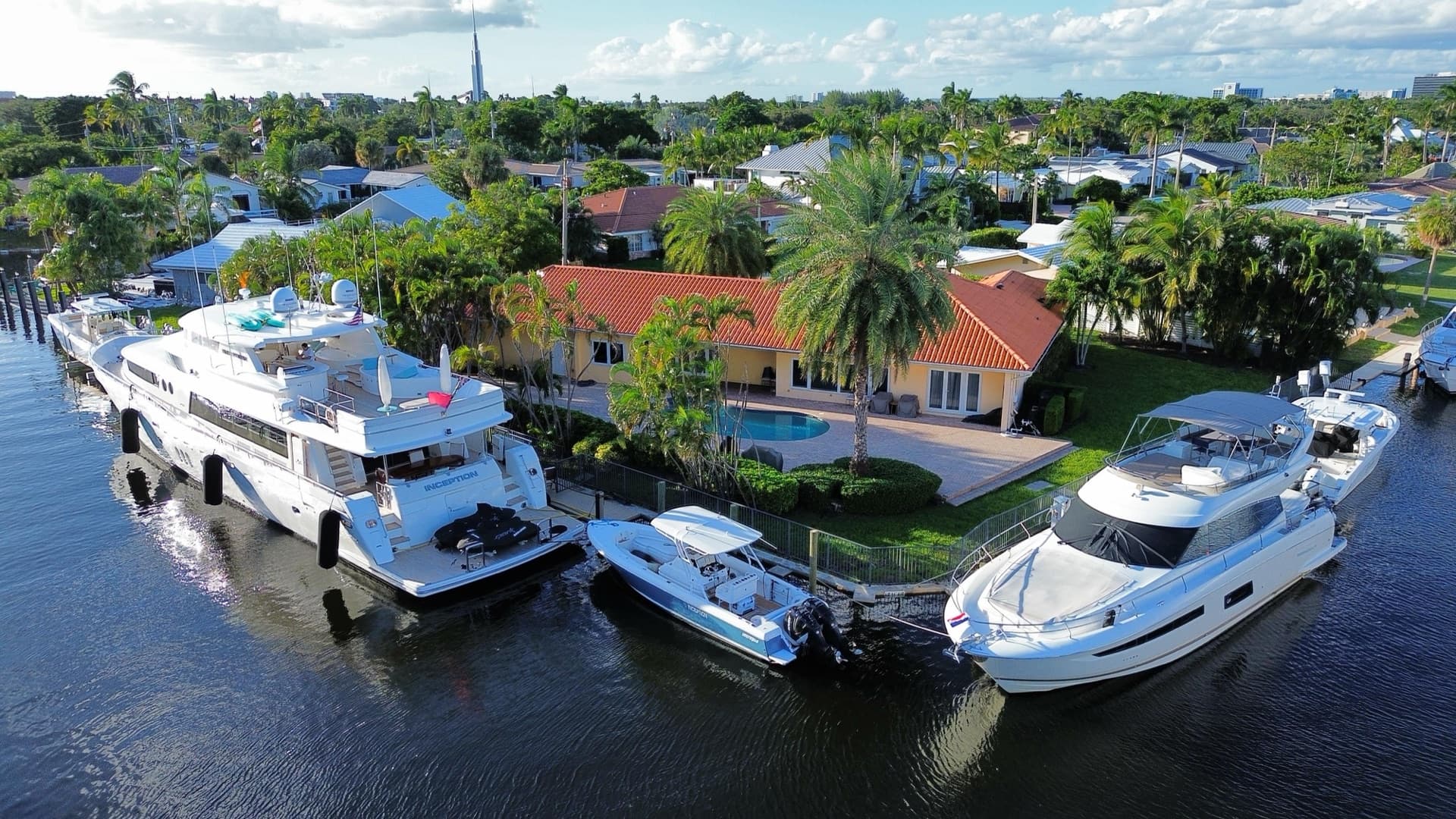 Yachts docked beside bright waterfront homes and palms in South Florida